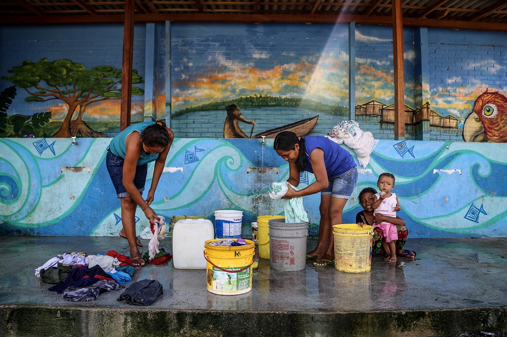 Mulheres lavam roupas no abrigo indígena de Pintolândia, em Boa Vista. As condições de abastecimento de água e saneamento são precárias no abrigo.