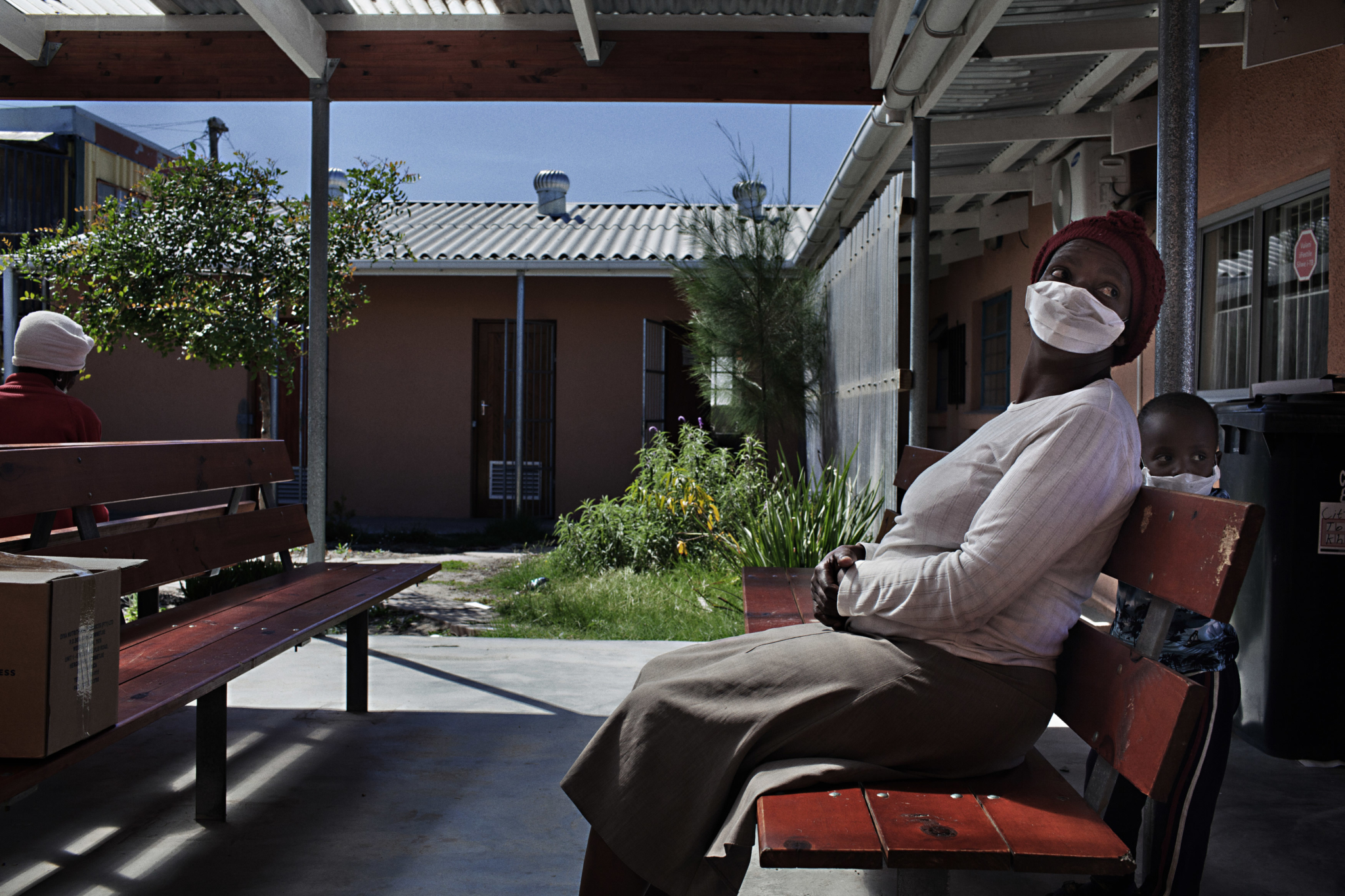 Mulher e filho na sala de espera aberta da Clínica para tratamento de tuberculose Mayenzeke, localizada na comunidade de Khayelitsha, perto da Cidade do Cabo, na África do Sul. © Jose Cendon