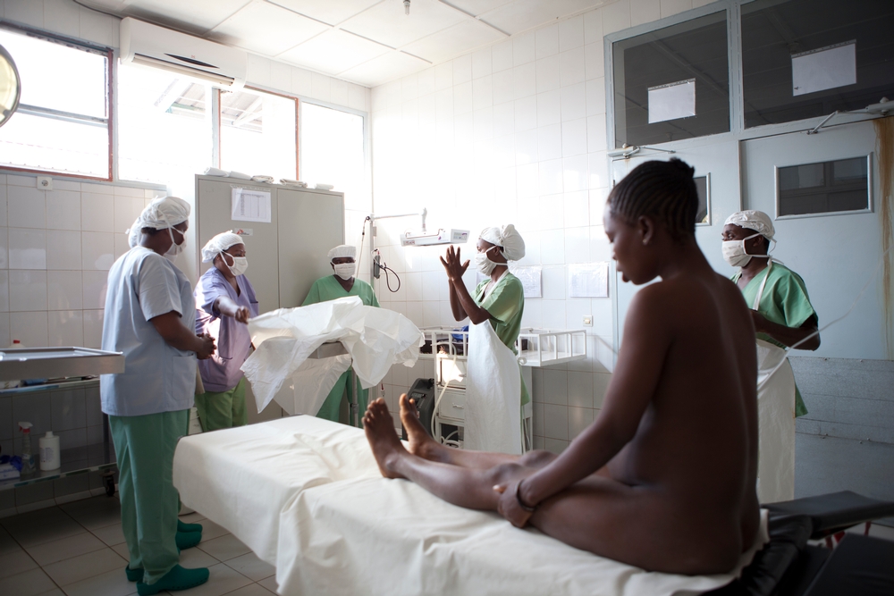 Ao fundo, a equipe cirúrgica de MSF se prepara para o procedimento. Durante o parto, as enfermeiras e a parteira estarão ao lado de Chantal para prestar assistência.