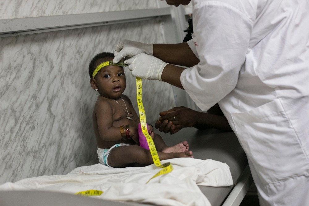 A dra. Marie Claire examina a bebê Nubia durante sua última visita à clínica de MSF. Apesar do encerramento do projeto, Nubia e seu meio-irmão MBemba, que também sobreviveu ao Ebola, serão acompanhados por equipes de MSF até que completem 2 anos de idade.