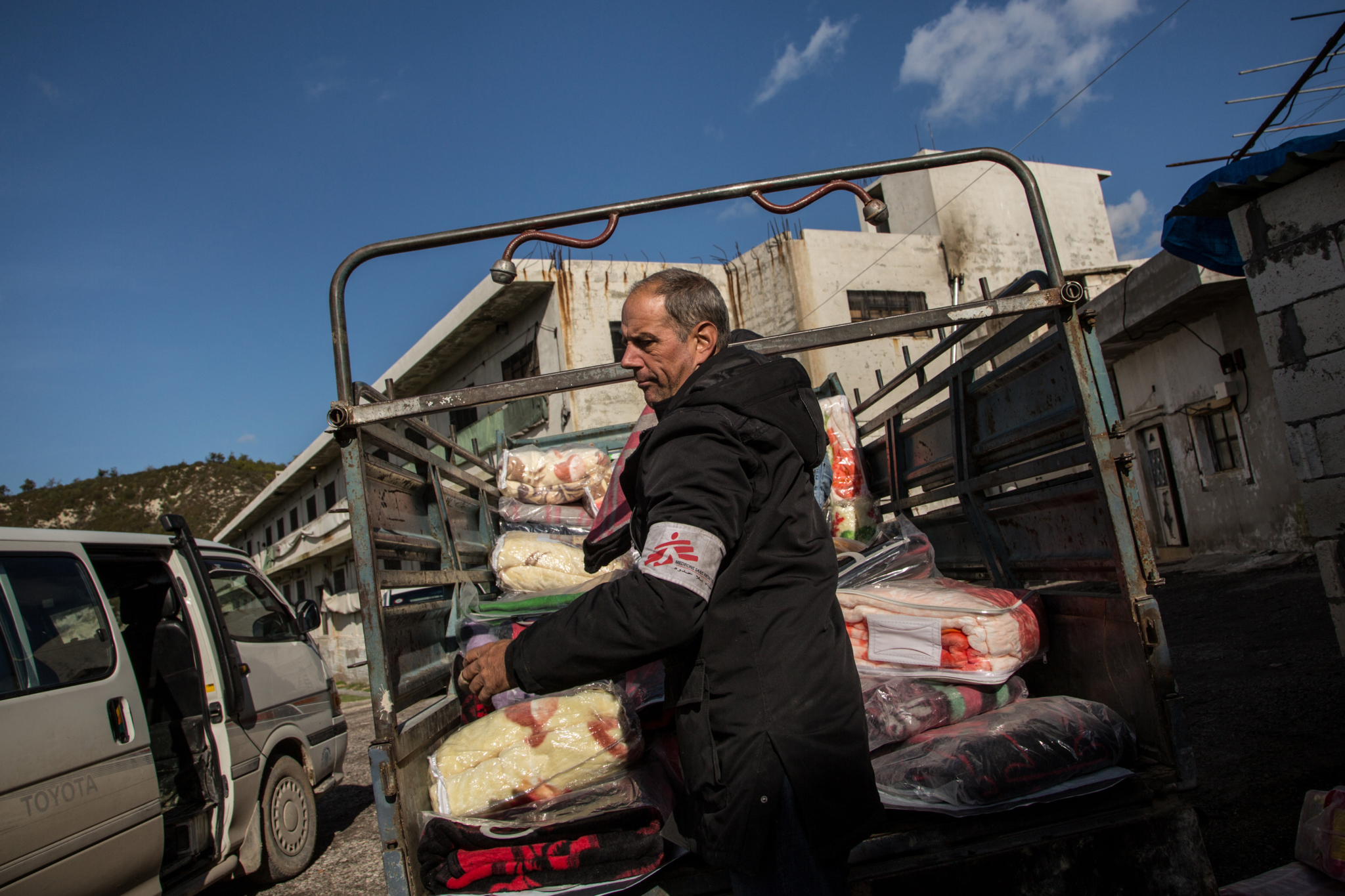 O coordenador logístco John Bunnel carrega a caminhoneta com cobertores, fraldas e outros itens de necessidade básica que serão distribuídos para deslocados internos sírios no norte do país. As equipes de MSF estão, também, provendo cuidados médicos e cirúrgicos a refugiados sírios em países vizinhos, como a Jordânia, o Líbano e o Iraque.