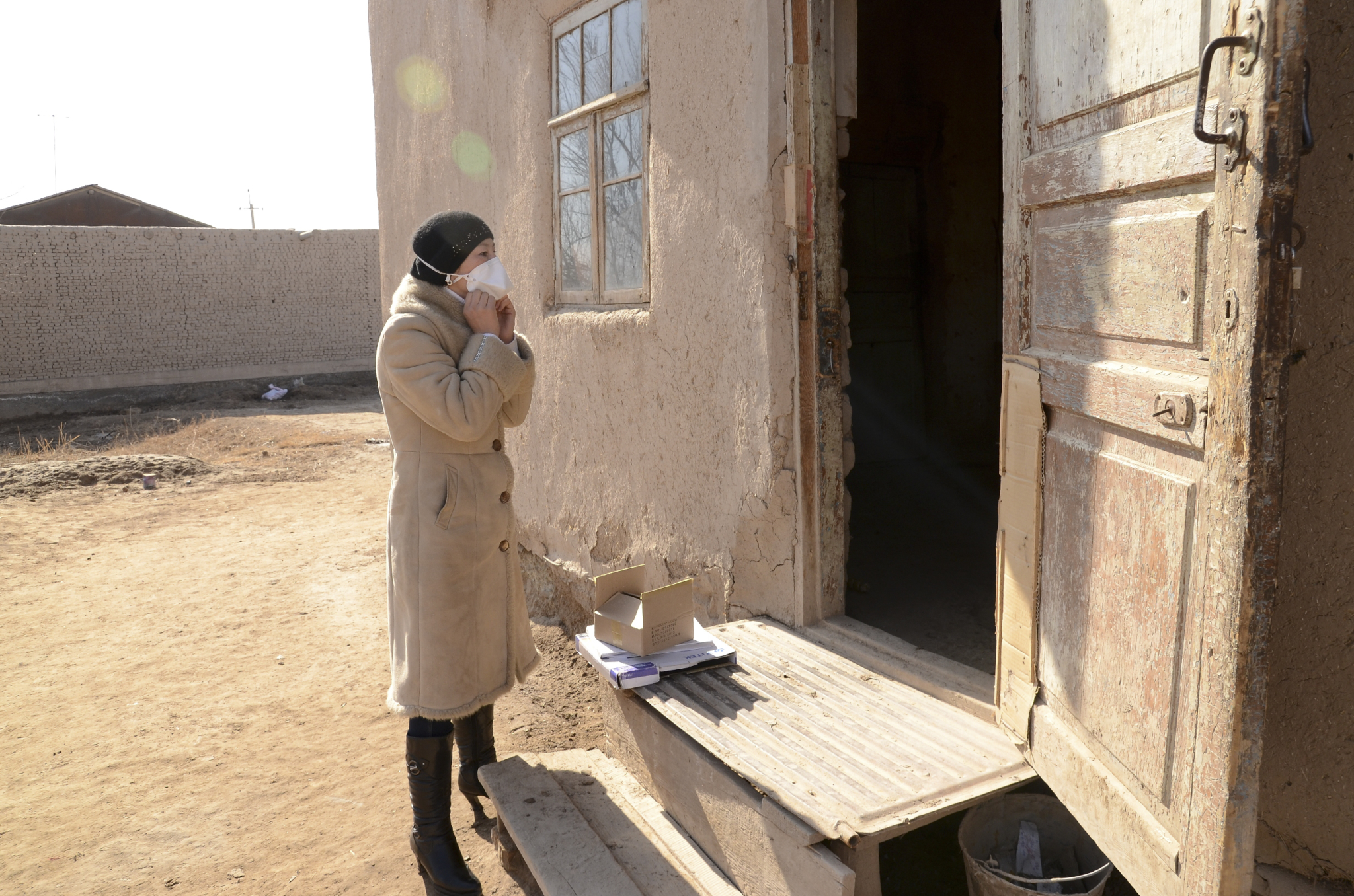 A enfermeira comunitária Sayyora coloca uma máscara quando chega à porta da casa da paciente de TB multirresistente em Hojeily, Karakalpakstan. Ela visita, diariamente, a casa dos seus pacientes, levando doses diárias de medicamentos contra a doença e comprimidos contra os efeitos colaterais. Ela também aplica injeções com outro medicamento contra a tuberculose, além de controlar o peso dos pacientes e os novos efeitos colaterais causados pelo tratamento. © Andriy Slizkiy