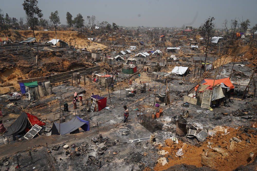 As pessoas começam a reconstruir abrigos entre os restos queimados de uma parte do acampamento de refugiados Cox's Bazar para o povo Rohingya, que foi destruída pelo fogo. Bangladesh, março de 2021.