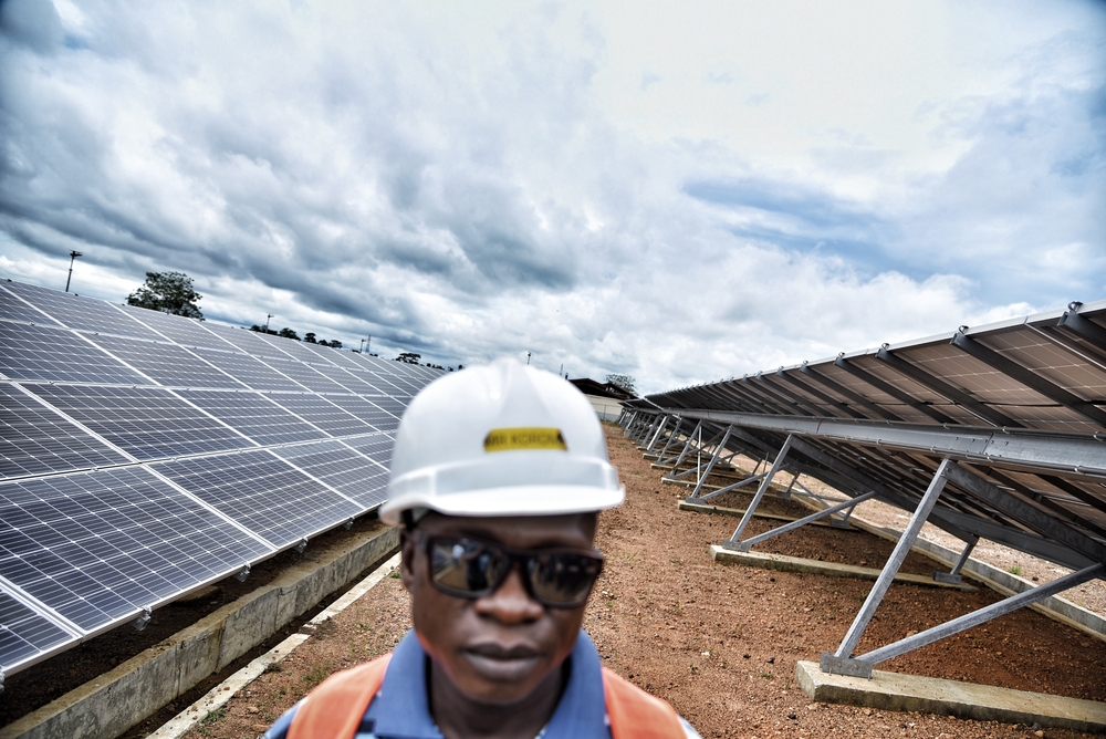 O supervisor de logística, Mohammed Korma, está em meio aos painéis solares que MSF instalou para administrar o hospital de Hangha com energia limpa. Distrito de Kenema, Serra Leoa, Junho de 2021.