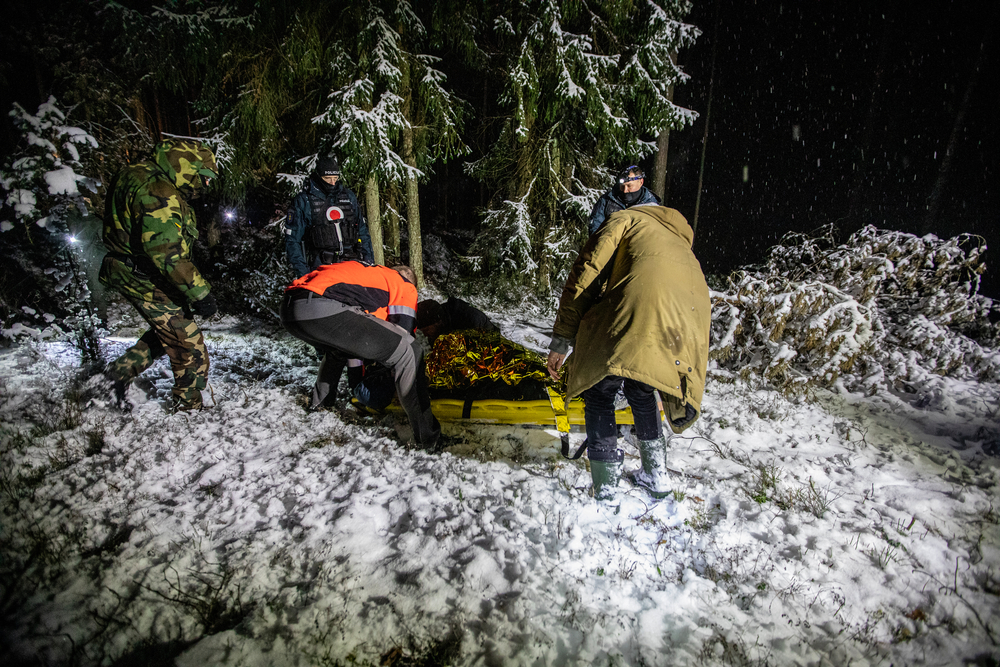 Profissionais de emergência da Lituânia se preparam para levar ao hospital um homem debilitado após atravessar a fronteira de Belarus.      Foto: Vidmantas Balkunas/BNS, Lituânia, dezembro de 2021.