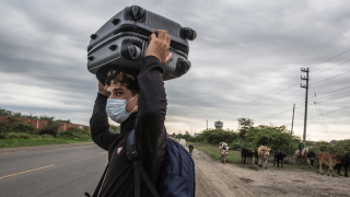 Um migrante venezuelano de 26 anos carrega seus pertences pela Rodovia Pan-Americana enquanto tenta chegar a Tumbes, no Peru. © Max Cabello Orcasitas