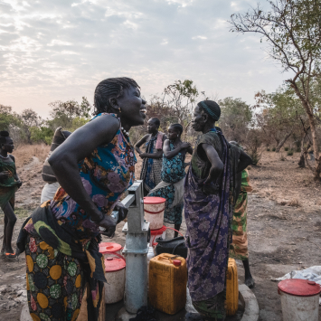Sera James a resident of Akello village, draws water from the bore hole as she shares a laugh with her friends.