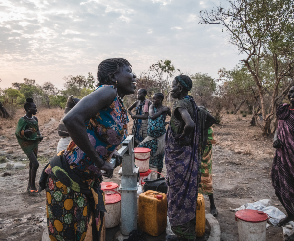 Sera James a resident of Akello village, draws water from the bore hole as she shares a laugh with her friends.