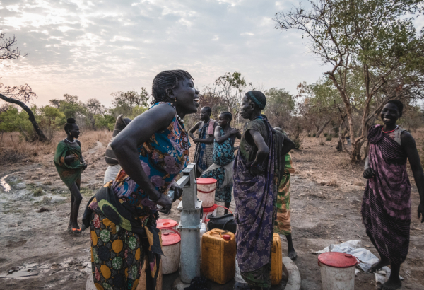 Sera James, moradora da comunidade de Akello, no Sudão do Sul, retira água do poço enquanto conversa com suas amigas. ©Njiiri Karago/MSF