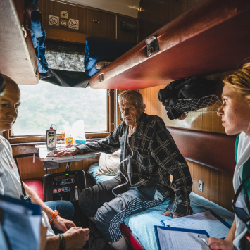 Médicos e enfermeiras a bordo do trem médico de MSF discutem a condição de um paciente durante a viagem de Pokrovsk, no leste da Ucrânia, maio de 2022 © Andrii Ovod