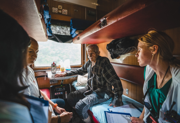 Médicos e enfermeiras a bordo do trem médico de MSF discutem a condição de um paciente durante a viagem de Pokrovsk, no leste da Ucrânia, maio de 2022 © Andrii Ovod