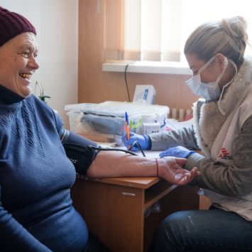MSF doctor Olena Kurinna checking Anna Ivanivna Nefedova’s blood pressure in the Tsyrkuny village town hall, Kharkiv region. The ambulatory clinic of the village was destroyed in the fighting. Like Anna Ivanivna Nefedova, most patients MSF patients in the rural towns and villages of the Kharkiv region are babushkas, the Ukrainian older women and grandmothers. Many of them already living with disabilities such as limited mobility, loss of hearing or sight, caused by age or uncontrolled chronic illnesses, such as hypertension and diabetes, are at risk of complications. Uncontrolled hypertension can lead to serious complications such as loss of sight, kidney failure, neurological impairment or even sudden death. The lack of doctors, nurses, medicines augmented by stress factors caused by the war have made controlling these conditions difficult.