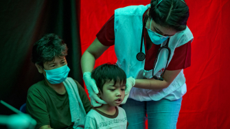 Profissional de MSF examina criança em um dos locais de busca ativa de casos de tuberculose de MSF, em Manila, nas Filipinas. © Ezra Acayan