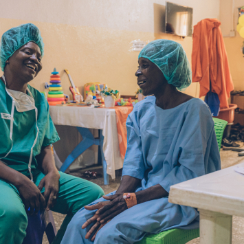 Aisha (à direita), paciente que recebe tratamento para noma em Sokoto, na Nigéria, com Funke Adagboyega, profissional de saúde mental de MSF.  Maio de 2023. Foto: Fabrice Caterini/Inediz