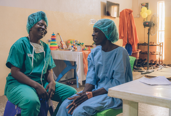 Aisha (à direita), paciente que recebe tratamento para noma em Sokoto, na Nigéria, com Funke Adagboyega, profissional de saúde mental de MSF.  Maio de 2023. Foto: Fabrice Caterini/Inediz