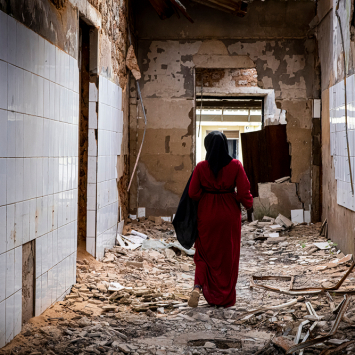 Echa, promotora de saúde mental de MSF que também sofreu violência durante o conflito em Cabo Delgado, caminha pelas alas destruídas do hospital geral de Mocímboa da Praia, no norte de Moçambique. © Nuria Lopez Torres/MSF