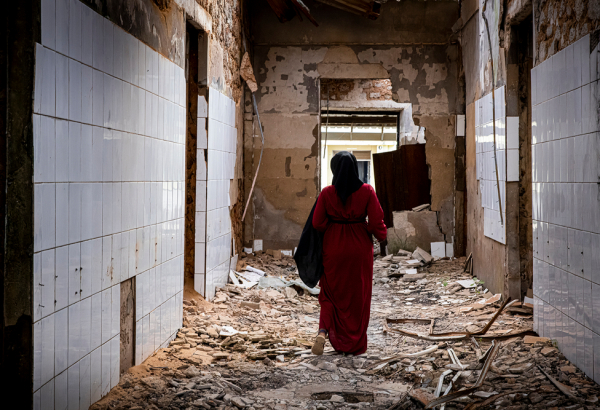 Echa, promotora de saúde mental de MSF que também sofreu violência durante o conflito em Cabo Delgado, caminha pelas alas destruídas do hospital geral de Mocímboa da Praia, no norte de Moçambique. © Nuria Lopez Torres/MSF