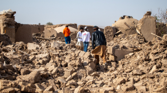 Equipe de MSF caminhando sobre os escombros de casas no vilarejo de Sanjaib, distrito de Injil, província de Herat. © Paul Odongo/MSF