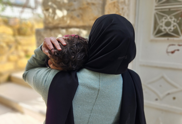 Aliyah*, mulher palestina que vive em Hebron, com a filha nos braços. Foto: Laora Vigourt/MSF