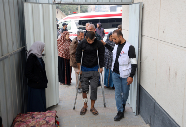 Profissional de MSF auxilia paciente com lesão na perna em uma clínica de cuidados pós-operatórios montada dentro do Hospital de Campanha Indonésio de Rafah, no sul de Gaza. Dezembro de 2023. © MSF