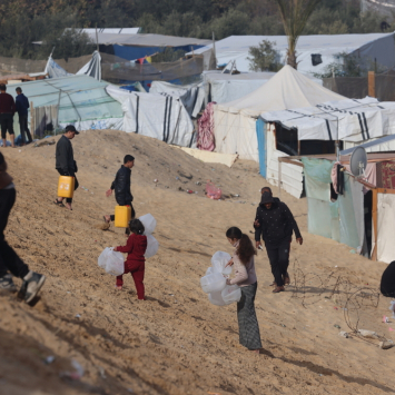 Palestinos deslocados pela guerra carregam garrafas vazias para um caminhão de água de MSF em Tal Al-Sultan, sul de Gaza. Janeiro de 2024. © MSF