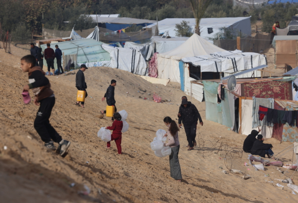 Palestinos deslocados pela guerra carregam garrafas vazias para um caminhão de água de MSF em Tal Al-Sultan, sul de Gaza. Janeiro de 2024. © MSF