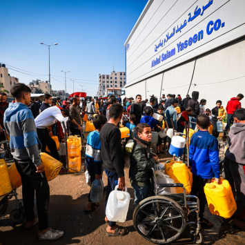Um grupo de palestinos deslocados espera pela distribuição de água de MSF na área de Tal Al-Sultan, na cidade de Rafah, sul de Gaza. Janeiro de 2024. © MSF