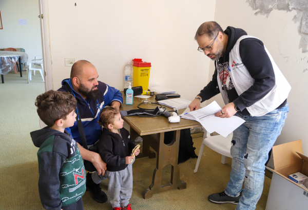 Ali e Elias acompanham o pai em uma consulta na unidade médica móvel de MSF em Al Merouaniye. Os dois irmãos estão entre as muitas crianças que se abrigam com suas famílias no Hotel Montana. © Maryam Srour/MSF