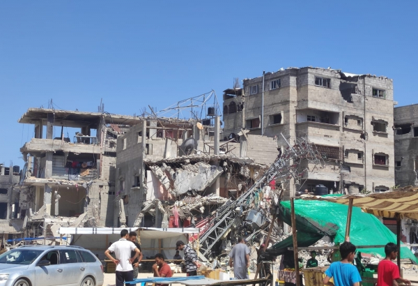 Pessoas em frente a um prédio bombardeado em Rafah. Faixa de Gaza, 10 de maio de 2024.
