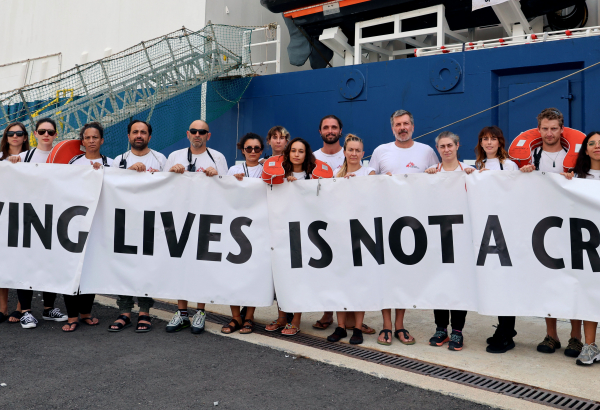 Profissionais de MSF que trabalham no Geo Barents, navio de resgate da organização, seguram faixa com mensagem “Saving lives is not a crime” (“Salvar vidas não é um crime”, em português). © Stefan Pejovic/MSF