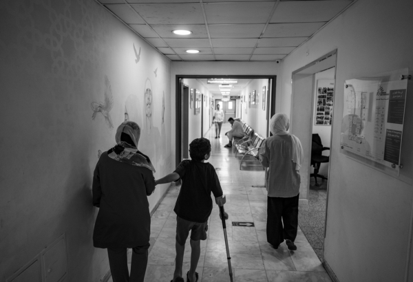 Hazem, de 8 anos (ao centro), caminha ao lado de sua mãe, Eman (à esquerda), e sua irmã, Deema (à direita), no corredor do hospital de cirurgia reconstrutiva de MSF em Amã, Jordânia, em 27 de agosto de 2024. Eles foram evacuados de Gaza. ©Moises Saman