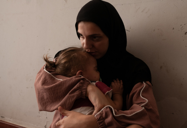 Zeinab Ozeir acalma Abbas, seu filho de 1 ano e meio, em um quarto onde vive com o marido e seus quatro filhos no abrigo Azarieh, no centro de Beirute. Líbano. © Antoni Lallican/Hans Lucas