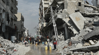 Pessoas coletam água ao lado de um prédio que corre o risco de desabar em Beit Lahia. Norte de Gaza, 3 de fevereiro de 2025. © Nour Alsaqqa/MSF