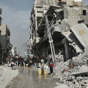 Pessoas coletam água ao lado de um prédio que corre o risco de desabar em Beit Lahia. Norte de Gaza, 3 de fevereiro de 2025. © Nour Alsaqqa/MSF