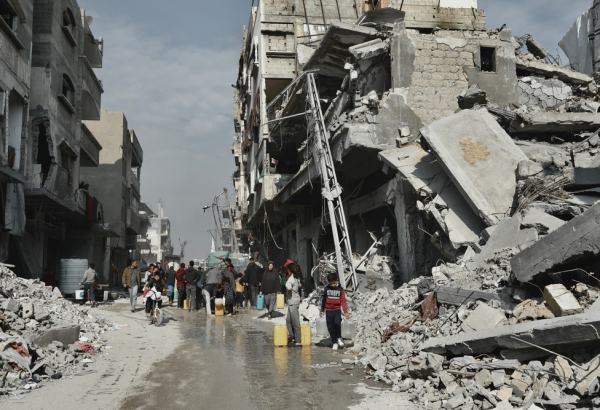 Pessoas coletam água ao lado de um prédio que corre o risco de desabar em Beit Lahia. Norte de Gaza, 3 de fevereiro de 2025. © Nour Alsaqqa/MSF