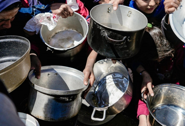Crianças palestinas seguram panelas vazias em uma cozinha comunitária. Norte de Gaza, fevereiro de 2025. ©Nour Alsaqqa/MSF
