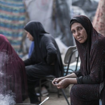 Hanan, mulher palestina, cozinha com fogo aceso de forma improvisada, a única maneira de alimentar sua família. Gaza, maio de 2025. ©Motassem Abu Aser
