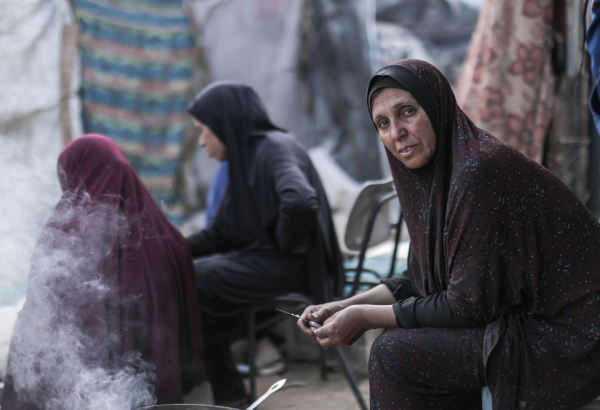 Hanan, mulher palestina, cozinha com fogo aceso de forma improvisada, a única maneira de alimentar sua família. Gaza, maio de 2025. ©Motassem Abu Aser