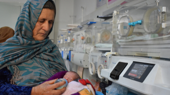 Reza Gul alimenta o neto, que nasceu prematuro, na ala neonatal do Hospital Regional Mazar-i-Sharif, apoiado por MSF, na província de Balkh, Afeganistão. ©Logan Turner/MSF