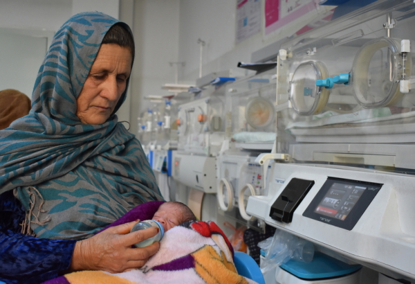 Reza Gul alimenta o neto, que nasceu prematuro, na ala neonatal do Hospital Regional Mazar-i-Sharif, apoiado por MSF, na província de Balkh, Afeganistão. ©Logan Turner/MSF