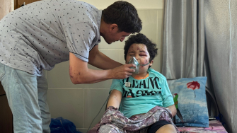 Kareem, 8 anos, é amparado pelo pai, Ahmed, cirurgião de MSF, após ser ferido em um ataque aéreo à sua casa na cidade de Gaza, em 27/06. @ Nour Alsaqqa/MSF