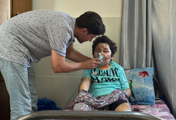 Kareem, 8 anos, é amparado pelo pai, Ahmed, cirurgião de MSF, após ser ferido em um ataque aéreo à sua casa na cidade de Gaza, em 27/06. @ Nour Alsaqqa/MSF