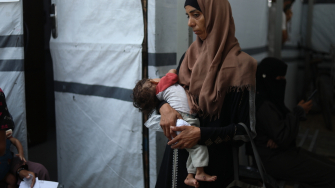 Ola segura seu filho de oito meses, Nour Al-Shaer, que sofre de desnutrição grave. Gaza, Palestina, agosto de 2025. © Nour Alsaqqa