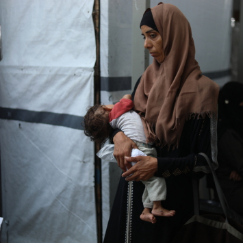 Ola segura seu filho de oito meses, Nour Al-Shaer, que sofre de desnutrição grave. Gaza, Palestina, agosto de 2025. © Nour Alsaqqa