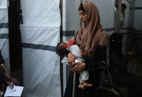 Ola segura seu filho de oito meses, Nour Al-Shaer, que sofre de desnutrição grave. Gaza, Palestina, agosto de 2025. © Nour Alsaqqa
