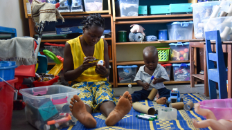 Morrison Williams, de 1 ano, e sua mãe, Adama, participam de uma sessão de brincadeira no Hospital Materno-Infantil de MSF em Kenema, Serra Leoa. ©Mary Dumbuya/MSF