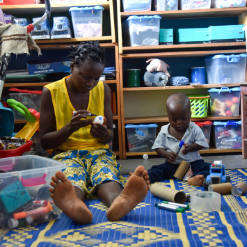 Morrison Williams, de 1 ano, e sua mãe, Adama, participam de uma sessão de brincadeira no Hospital Materno-Infantil de MSF em Kenema, Serra Leoa. ©Mary Dumbuya/MSF