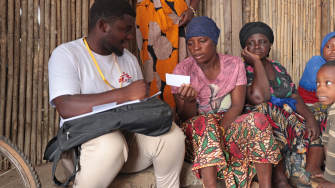 Issa Manzi Makaburi, promotor de saúde de MSF, entrega um documento de encaminhamento a uma mulher deslocada no acampamento de Lianda, Moçambique. © Sofia Minetto