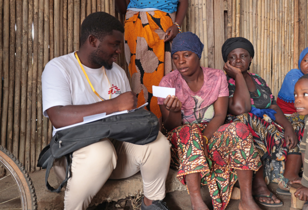 Issa Manzi Makaburi, promotor de saúde de MSF, entrega um documento de encaminhamento a uma mulher deslocada no acampamento de Lianda, Moçambique. © Sofia Minetto