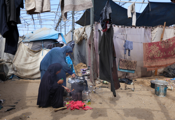 Mãe e filha deslocadas pela guerra em Gaza preparam uma refeição com métodos improvisados e inseguros em uma tenda em Mawasi, Khan Younis. ©Motasem Abu Aser/MSF